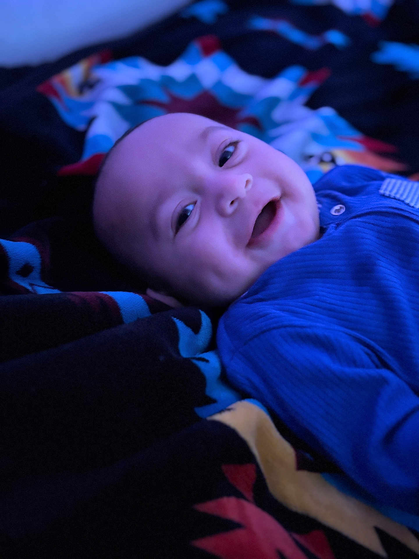 Toa-Malosi is registered to the contest to win money with this photo: baby, blanket, blue_clothing, child, closeup, cozy, cute, dimples, face, happy, indoor, infant, lying_down, patterned_blanket, person, portrait, sleepwear, smiling, soft_lighting, warmth