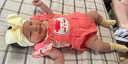 Ashanti Dafne is registered to the contest to win money with this photo: baby, infant, bed, plaid, headband, bow, clothing, coral, yellow, socks, cute, face, smiling, lying_down, indoor, child, person, apparel, pattern, soft