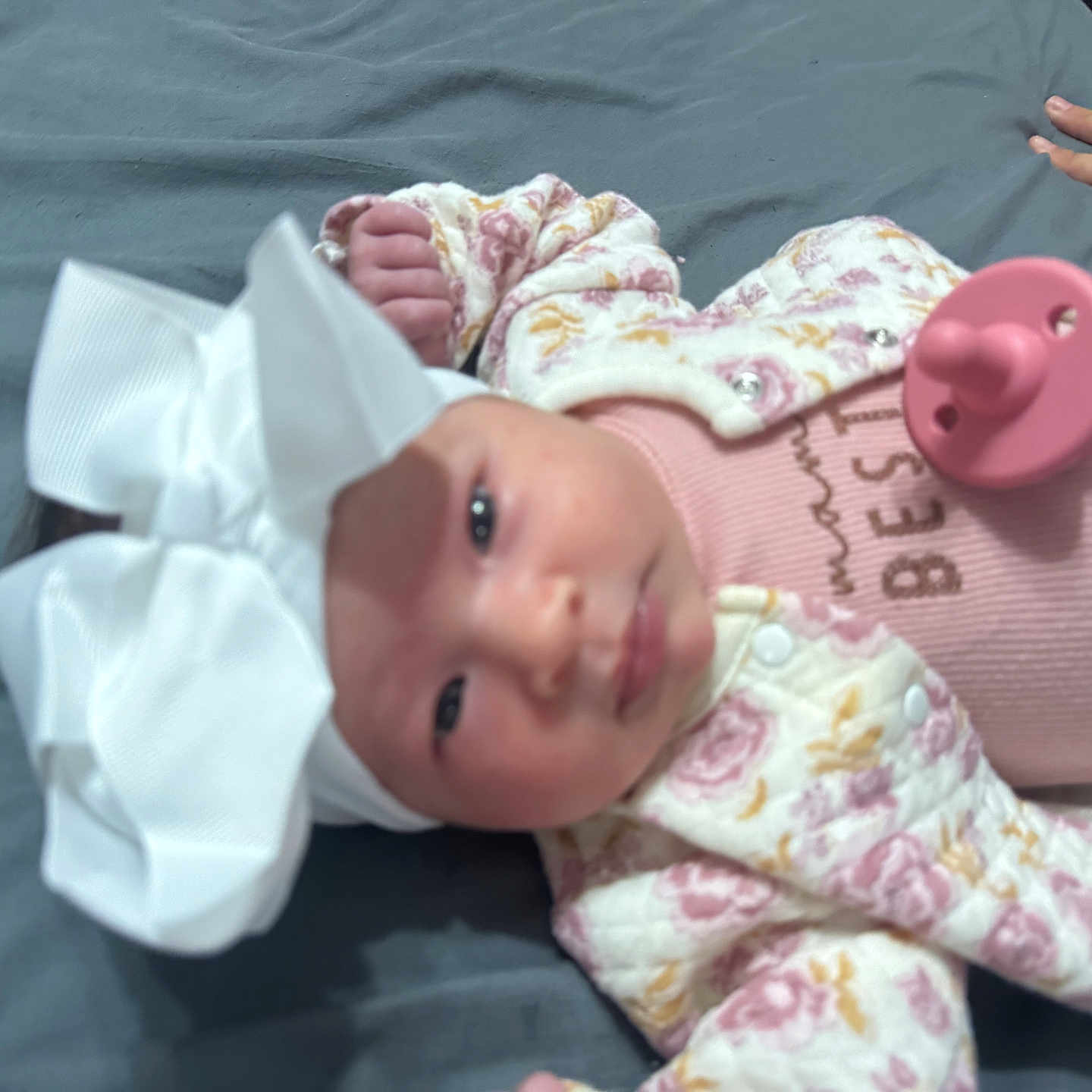 Ashanti Dafne joined the competition — help win amazing prizes! baby, bow, child, closeup, cute, floral_jacket, gray_background, hands, headwear, human, indoors, infant, lying_down, newborn, pacifier, pink_clothing, portrait, sleepwear, small_hands, soft_toys