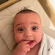 Isaac-George joined the competition — help win amazing prizes! baby, infant, face, hand, blanket, quilt, mohawk, skin, expression, cute, child, person, lying_down, indoors, comfort, young, wrapped, portrait, curious, fingers