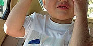 Xavier joined the competition — help win amazing prizes! child, glasses, car_interior, white_tshirt, blue_design, seatbelt, window, seat, hand, face, hair, playful, young, casual, sunlight, portrait, child_in_car, adjusting_glasses, red_frames, expression