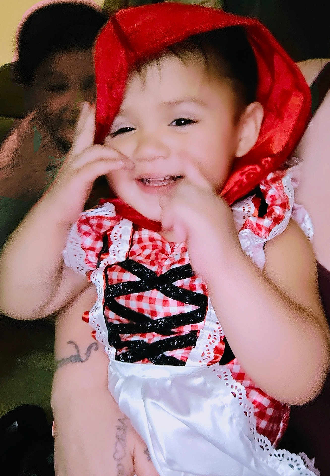 Debani is registered to the contest to win money with this photo: child, toddler, smiling, red_hood, checkered_dress, playful, happy, portrait, indoor, person, cute, baby, family, hand_gesture, face, childhood, people, background, blurred, holding