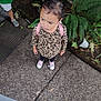 toddler, child, backpack, leopard_print, sneakers, sidewalk, outdoor, plants, greenery, concrete, curious, standing, casual_clothing, person, nature, small_child, footwear, daylight, urban, looking_up