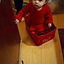Debani is registered to the contest to win money with this photo: bag, candid, child, curious, cute, door, floor, holding, home, indoor, kitchen, person, playing, pot, red_sweater, sitting, small_bag, toddler, wooden_floor, young_child