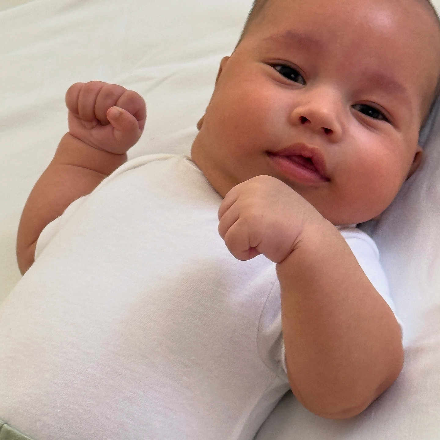 Abdullokhon is registered to the contest to win money with this photo: baby, cheeks, child, closeup, cute, expression, face, fists, head, indoors, infant, lying_down, newborn, person, portrait, resting, skin, soft_background, white_clothing, young