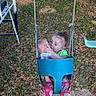 child, swing, doll, playground, outdoor, grass, leaves, pink_pants, green_shirt, toy, play, fun, happy, person, nature, seat, chain, metal, face, expression