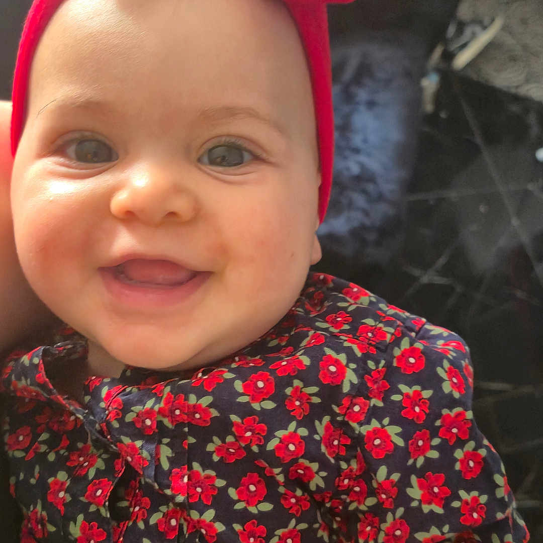 Becky joined the competition — help win amazing prizes! baby, child, smiling, face, headband, bow, red, floral_pattern, clothing, portrait, happy, cute, infant, indoors, person, skin, hand, bright_eyes, closeup, fashion