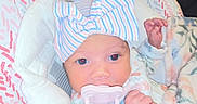 Caliyah is registered to the contest to win money with this photo: baby, child, pacifier, bow, striped_bow, blanket, cushion, infant, cute, face, headwear, sleeping_bag, indoors, portrait, closeup, person, young_child, resting, soft_lighting, comfortable