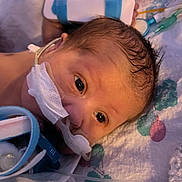 Alfie joined the competition — help win amazing prizes! newborn, baby, infant, medical_tubes, pacifier, blanket, hospital, face, closeup, eyes, skin, head, person, healthcare, care, fragile, lying_down, pattern, blue, white