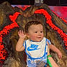 Lucas is registered to the contest to win money with this photo: baby, child, nike, bib, hand, face, person, lava, volcano, glow, red, brown, blue, clothing, smiling, indoor, background, waving, holding, young