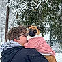 person, dog, pug, winter, snow, tree, jacket, glasses, outdoor, cold, pet, coat, hug, animal, nature, fence, curly_hair, snowy, portrait, cuddling