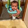 baby, babygear, bed, bedroom, carpet, child, clothing, cute, doorframe, doorway, expression, floor, indoor, infant, jumper, person, play, sitting, tag, wood
