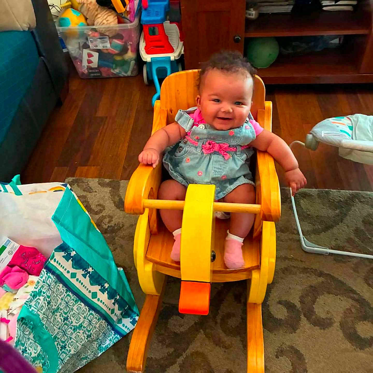 Montina joined the competition — help win amazing prizes! baby, carpet, child, colorful, curly_hair, floor, furniture, happy, indoor, living_room, pink_clothing, plastic_container, play, rocking_horse, seat, smiling, socks, storage_box, toy, wooden_chair