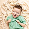 baby, blanket, button_up, casual, child, cute, fabric, face, green_shirt, hairstyle, happy, indoor, lying_down, person, playful, portrait, shorts, skin, smiling, toddler