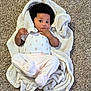 baby, blanket, carpet, infant, child, cute, cozy, lying_down, curious, soft_texture, indoor, person, toddler, clothing, footed_pants, hand, face, expression, curled_blanket, infancy