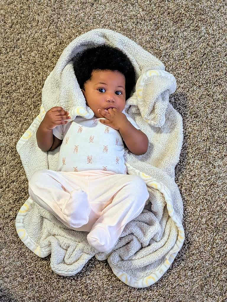 Cayra is registered to the contest to win money with this photo: baby, blanket, carpet, infant, child, cute, cozy, lying_down, curious, soft_texture, indoor, person, toddler, clothing, footed_pants, hand, face, expression, curled_blanket, infancy