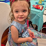Kyrah joined the competition — help win amazing prizes! child, birthday_girl, party, dress, headband, chair, table, party_hat, snack_bag, gift_bag, celebration, smiling, happy, indoor, curly_hair, blue_dress, stars, sparkle, young_girl, festive