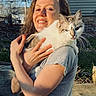 woman, cat, outdoor, sunlight, smiling, pet, animal, human, feline, shoulder, grey_shirt, wooden_fence, house, grass, daylight, happy, nature, portrait, casual, friendly