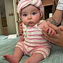 baby, infant, knitwear, striped_clothing, turban, hand, tattoo, bed, quilt, indoor, person, cute, child, blue_eyes, soft_lighting, portrait, skin, sitting, supporting_hand, cozy