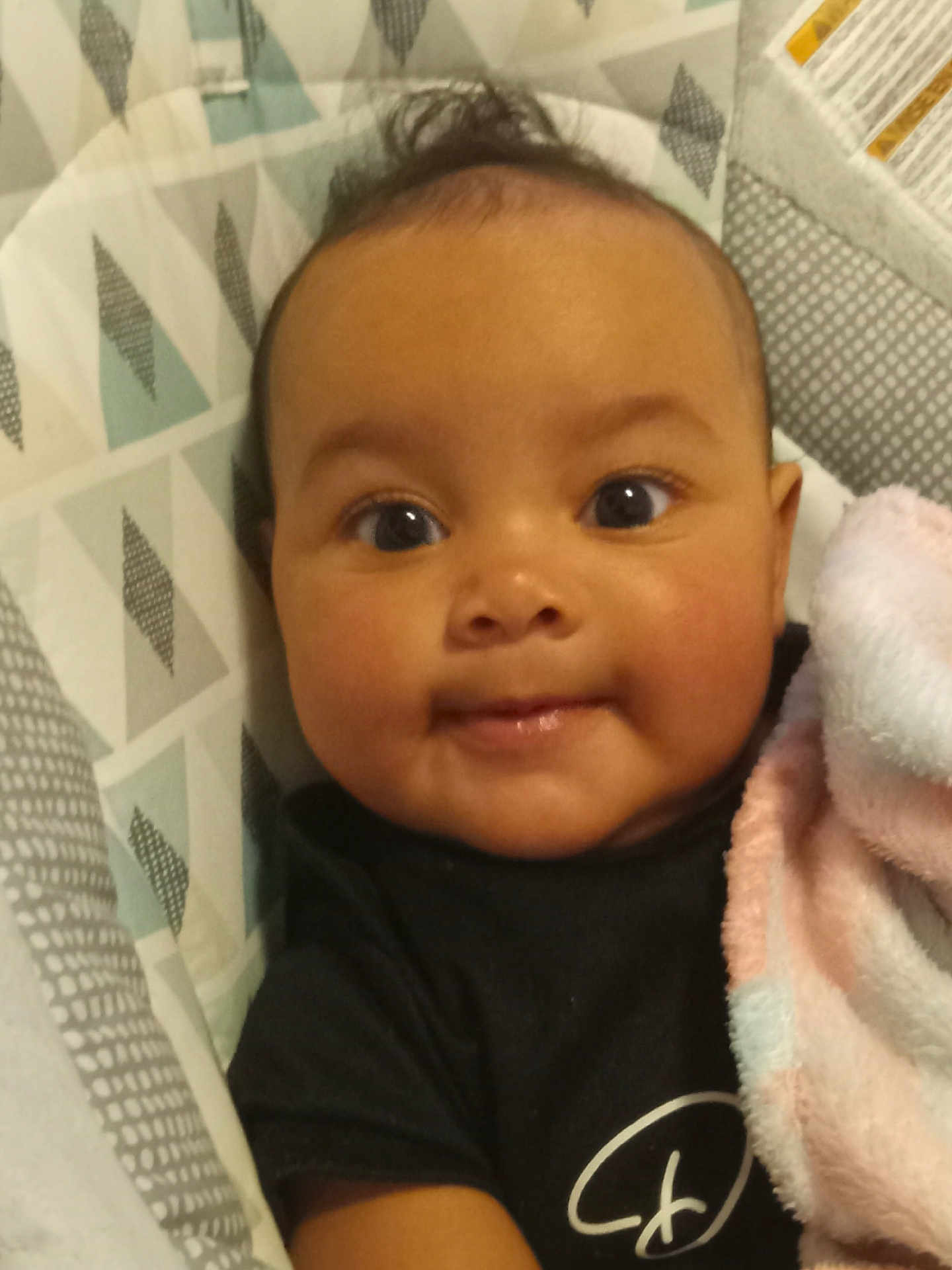 Yanny joined the competition — help win amazing prizes! baby, infant, face, smile, eyes, blanket, black_clothing, patterned_background, cute, closeup, child, indoors, soft_texture, cozy, person, portrait, happy, young, toddler, baby_seat