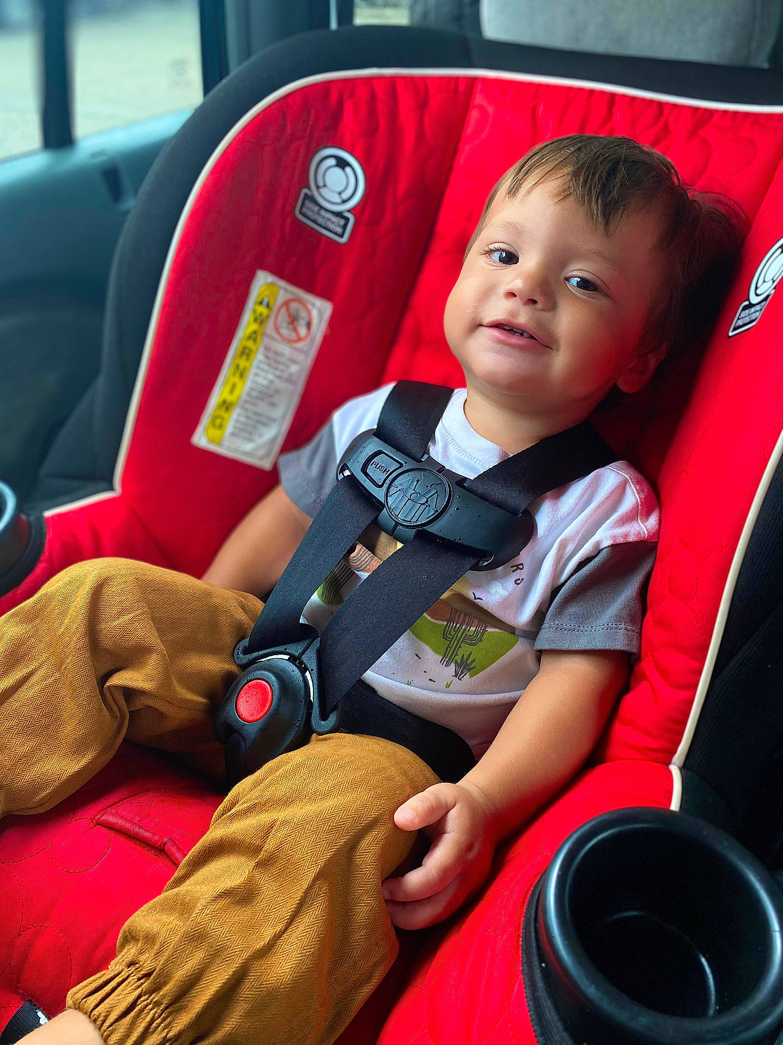 Amari is registered to the contest to win money with this photo: auto_part, automotive_design, automotive_tire, baby, baby_carriage, baby_products, baby_toddler_clothing, car_seat, car_seat_cover, child, comfort, face, motor_vehicle, person, red, seat_belt, sitting, smile, steering_wheel, toddler