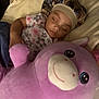 baby, sleeping, stuffed_animal, pink, bonnet, onesie, floral, cuddle, bedtime, soft_toy, child, indoors, blanket, cute, peaceful, rest, comfort, toy, person, portrait