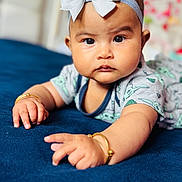 Ava joined the competition — help win amazing prizes! baby, child, infant, headband, bow, bracelet, hand, face, eyes, clothing, blue_blanket, soft_texture, portrait, closeup, indoors, curious, cute, decor, focus, expression