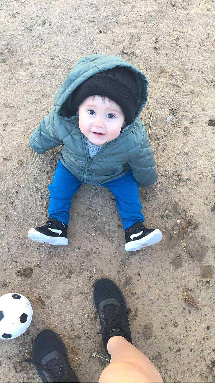 Kai is registered to the contest to win money with this photo: ball, child, electric_blue, eye, face, football, fun, grass, headwear, leisure, people_in_nature, person, recreation, sand, shoe, sitting, sleeve, smile, sneakers, toddler