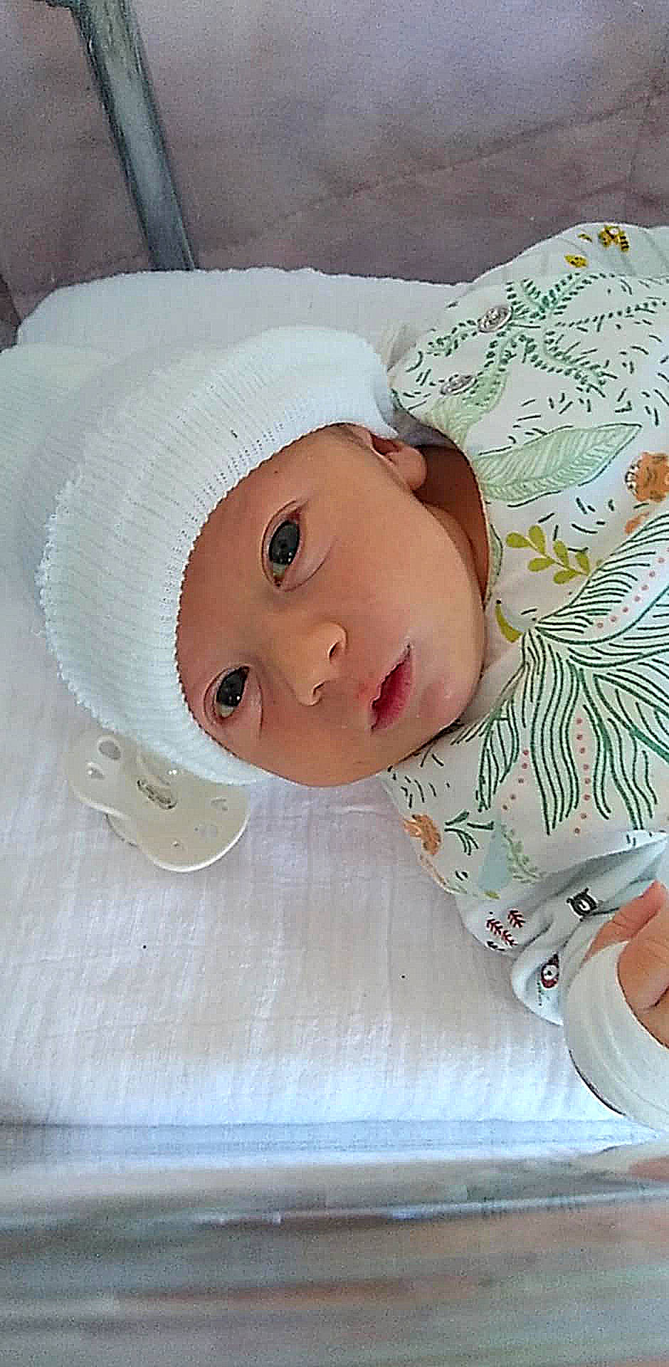 baby, beanie, bed, blanket, bonnet, cap, clothing, cradle, crib, face, furniture, hat, head, hosiery, infantbed, newborn, person, photography, portrait, sock