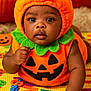alphabet, baby, child, costume, crawling, cute, eyes, face, green, halloween, hand, holiday, indoors, infant, orange, play_mat, pumpkin_costume, seasonal, smiling, toy