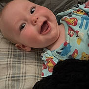Thomas joined the competition — help win amazing prizes! baby, infant, smiling, face, plaid_blanket, onesie, animal_print, lying_down, happy, child, soft_texture, black_fabric, cute, cheerful, indoors, closeup, head, expression, playful, young