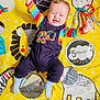 baby, infant, smiling, colorful_clothing, playmat, yellow_background, striped_shirt, overalls, blue_socks, child, happy, toy, mirror, elephant, lion, octopus, zebra, raised_arms, indoor, cute
