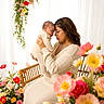 baby, woman, mother, infant, flowers, floral_arrangement, bench, knitwear, glasses, portrait, indoor, love, family, holding, peaceful, decor, warm_colors, seated, tenderness, cute