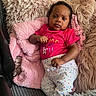 baby, infant, child, couch, pillow, blanket, pink, polka_dot, clothing, face, portrait, indoor, relaxing, cozy, furniture, cute, person, resting, smiling, home