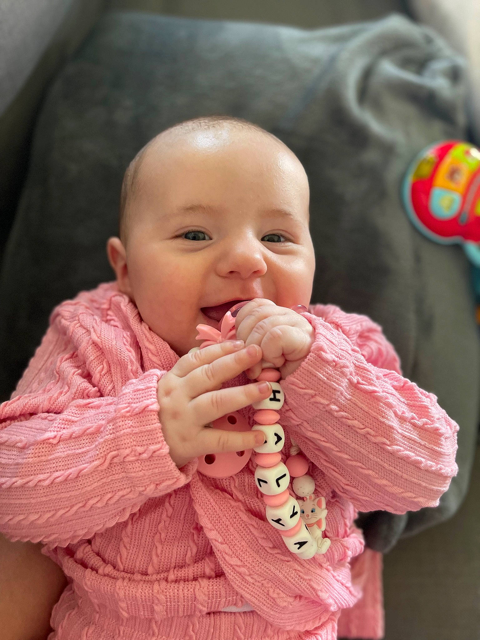 Thalya participe au concours pour gagner de l'argent avec cette photo : arm, baby, baby_toddler_clothing, cheek, child, dress, finger, gesture, hand, happy, lip, nose, outerwear, person, pink, skin, sleeve, smile, textile, thumb