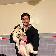 Bella joined the competition — help win amazing prizes! black_jacket, casual, companion, dog, domestic, fluffy, happy, holding, indoor, leash, man, pet, portrait, radiator, smile, tiled_wall, trash_bin, wall_outlet, white_dog, young_adult