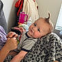 Asher joined the competition — help win amazing prizes! baby, child, smile, face, hair, mohawk, blanket, hand, person, indoor, furniture, bottle, table, cup, clothing, leopard_print, happy, cute, skin, holding