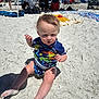 Asher is registered to the contest to win money with this photo: baby, child, beach, sand, sunlight, swimsuit, dinosaur, summer, outdoor, vacation, sunny, footwear, legs, people, umbrella, blanket, chair, shade, recreation, family