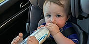Asher joined the competition — help win amazing prizes! baby, car_seat, milk_bottle, infant, child, car_interior, seatbelt, foot, hand, blue_clothing, window, trees, blurred_background, safety, curious_expression, pale_skin, short_hair, indoor, transportation, cute
