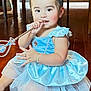 Princess is registered to the contest to win money with this photo: toddler, child, princess, dress, blue_dress, tiara, wand, jewelry, bracelet, ring, sitting, wooden_floor, indoor, playful, cute, young_child, costume, smiling, person, portrait