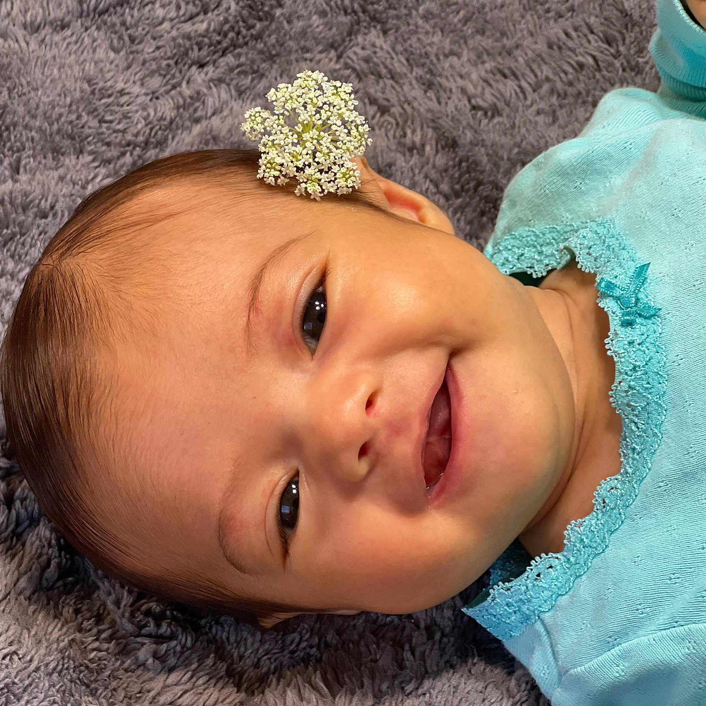 Isabella joined the competition — help win amazing prizes! baby, blanket, blue_clothing, child, closeup, cute, face, flower, happy, head, indoors, infant, lying_down, one_person, portrait, skin, small, smiling, toddler, young