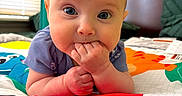 Magdalene is registered to the contest to win money with this photo: animal_print, baby, bedroom, blue_clothing, chewing, child, closeup, colorful, curious, cute, face, hands, head, indoor, infant, person, playmat, portrait, soft_lighting, young