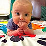 Magdalene is registered to the contest to win money with this photo: baby, infant, child, face, hands, blue_clothing, playmat, animal_print, indoor, bedroom, curious, chewing, cute, head, person, portrait, closeup, colorful, soft_lighting, young