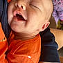 baby, infant, smiling, face, skin, orange_clothing, child, person, closeup, sleeping, hand, arm, texture, fabric, comfort, peaceful, cute, young, portrait, toddler