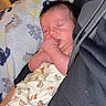 baby, sleeping, blanket, car_pattern, thumb_sucking, infant, cozy, indoor, person, child, cute, resting, soft_fabric, comfort, newborn, portrait, wrapped, peaceful, relaxation, clothing
