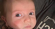 Ryker joined the competition — help win amazing prizes! baby, infant, onesie, clothing, person, face, eyes, hand, indoor, portrait, expression, curious, skin, hair, sitting, cuddle, shirt, text, closeup, cozy