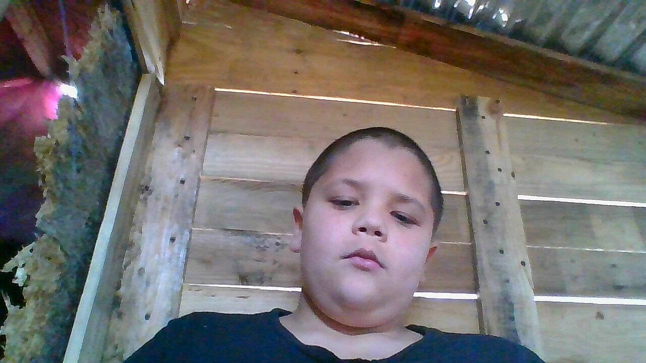 Coby is registered to the contest to win money with this photo: beam, beauty, buzz_cut, cheek, child, chin, crew_cut, eyelash, forehead, fun, hardwood, jaw, lumber, no_expression, person, plywood, t_shirt, tints_and_shades, toddler, wood