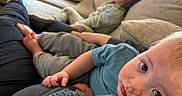 Titus joined the competition — help win amazing prizes! toddler, child, person, couch, sofa, living_room, clothing, sitting, relaxing, indoor, footwear, pants, shirt, pillow, hair, face, expression, skin, adult, home