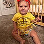 accessories, baby, clothing, costume, crib, cushion, face, furniture, head, homedecor, indoors, infantbed, pants, person, photography, portrait, shorts, sitting, t_shirt, wood