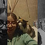 person, cat, indoor, calico_cat, glasses, hoodie, smile, pet, affection, wall, table, bottle, hair, face, casual, domestic, closeup, friendship, relaxation, home
